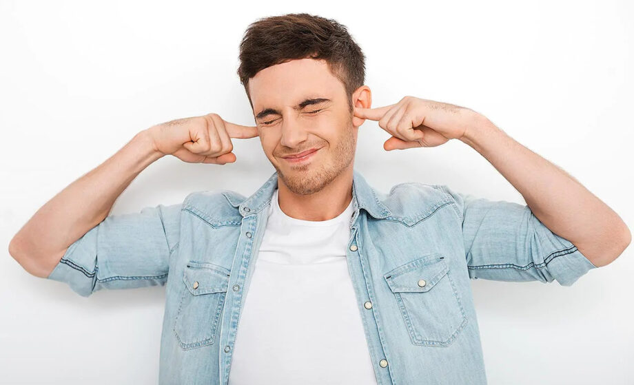 Persona tapándose los oídos en casa para protegerse del ruido de la calle