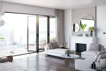 Ventanas plegables de PVC negras en salón moderno con sofá blanco